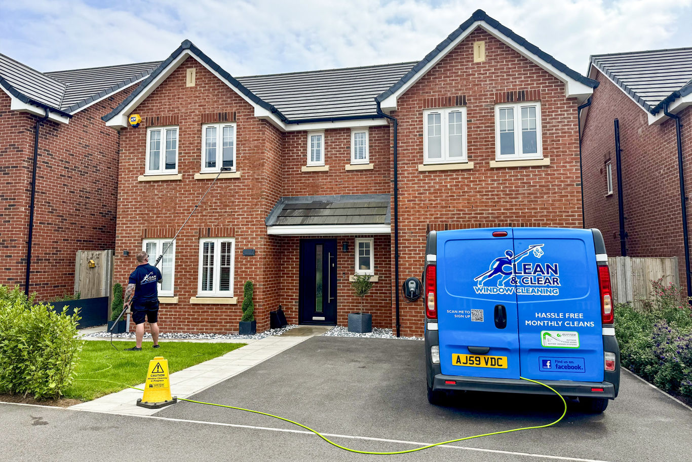 Man stood in front of large house cleaning front windows with his van on the drive. Man stood in front of large house cleaning front windows with his van on the drive.