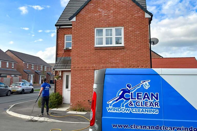Close up of clean and clear window cleaning van with man in background cleaning a residential property.